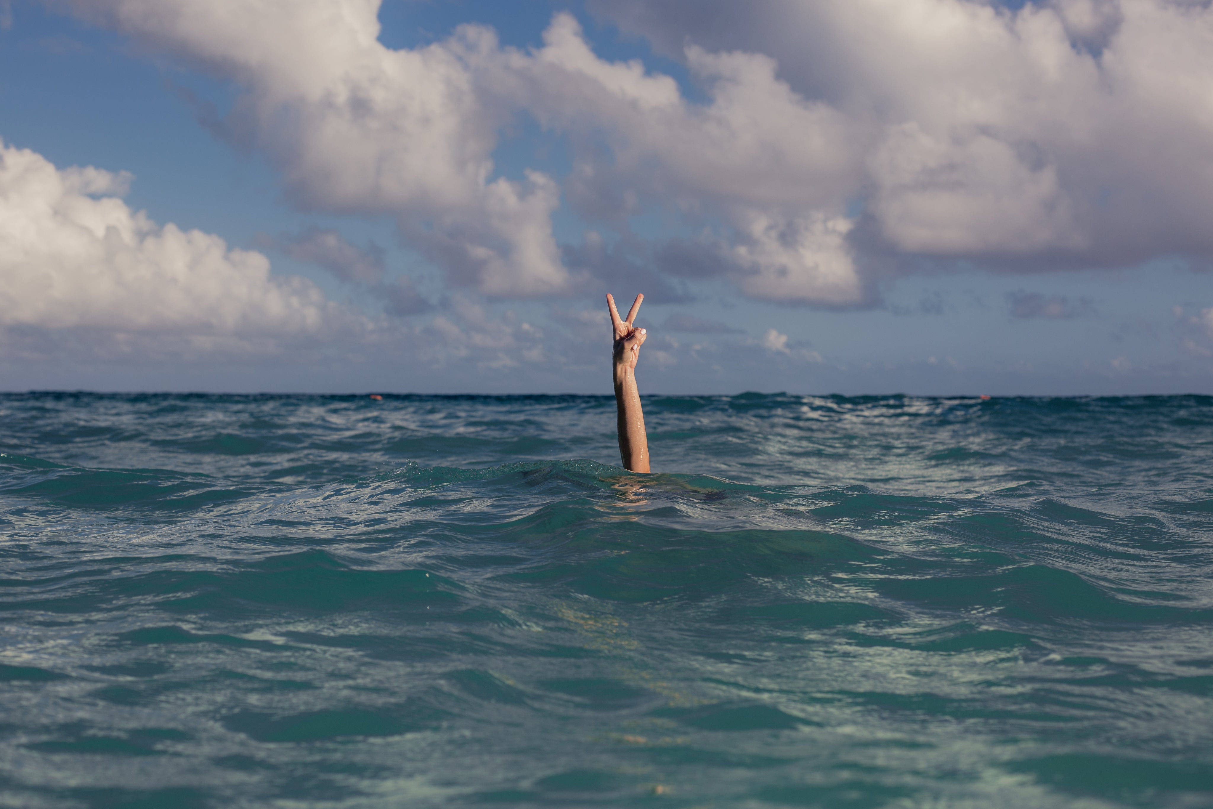 hand sticking out of water giving peace sign