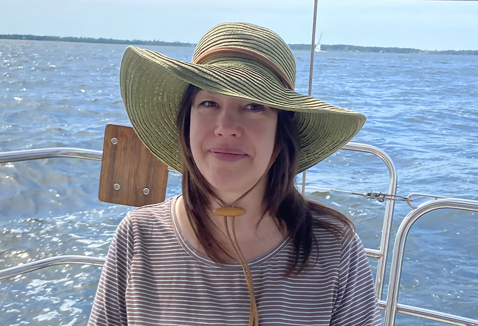 Shay, the founder of Salt Habit Skincare, at the helm of her sailboat